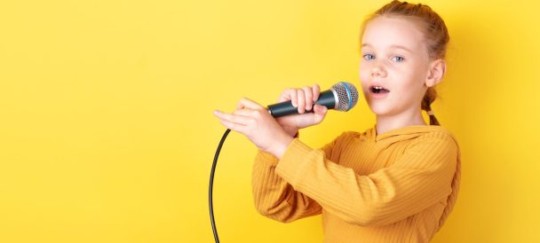 Dziewczynka z mikrofonem na żóltym tle