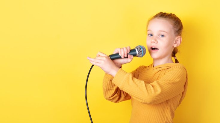 Dziewczynka z mikrofonem na żóltym tle