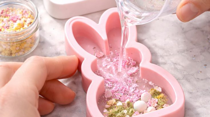 Silikownowa forma zajączka wypełniona ozdobami.